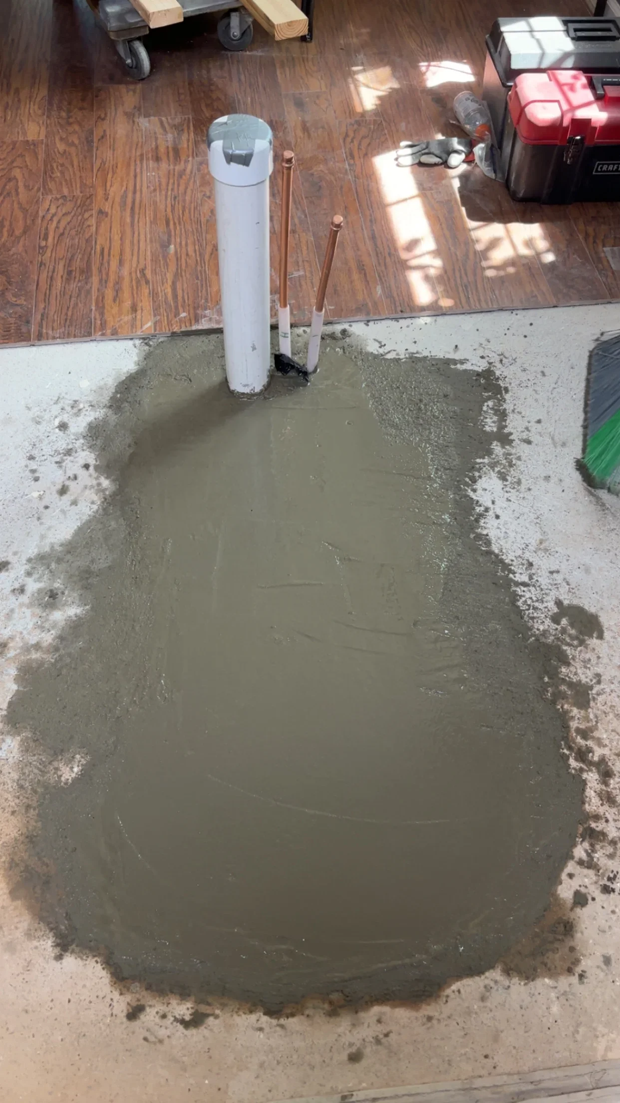 Self-leveling concrete patch with PVC pipe and copper fittings on concrete floor