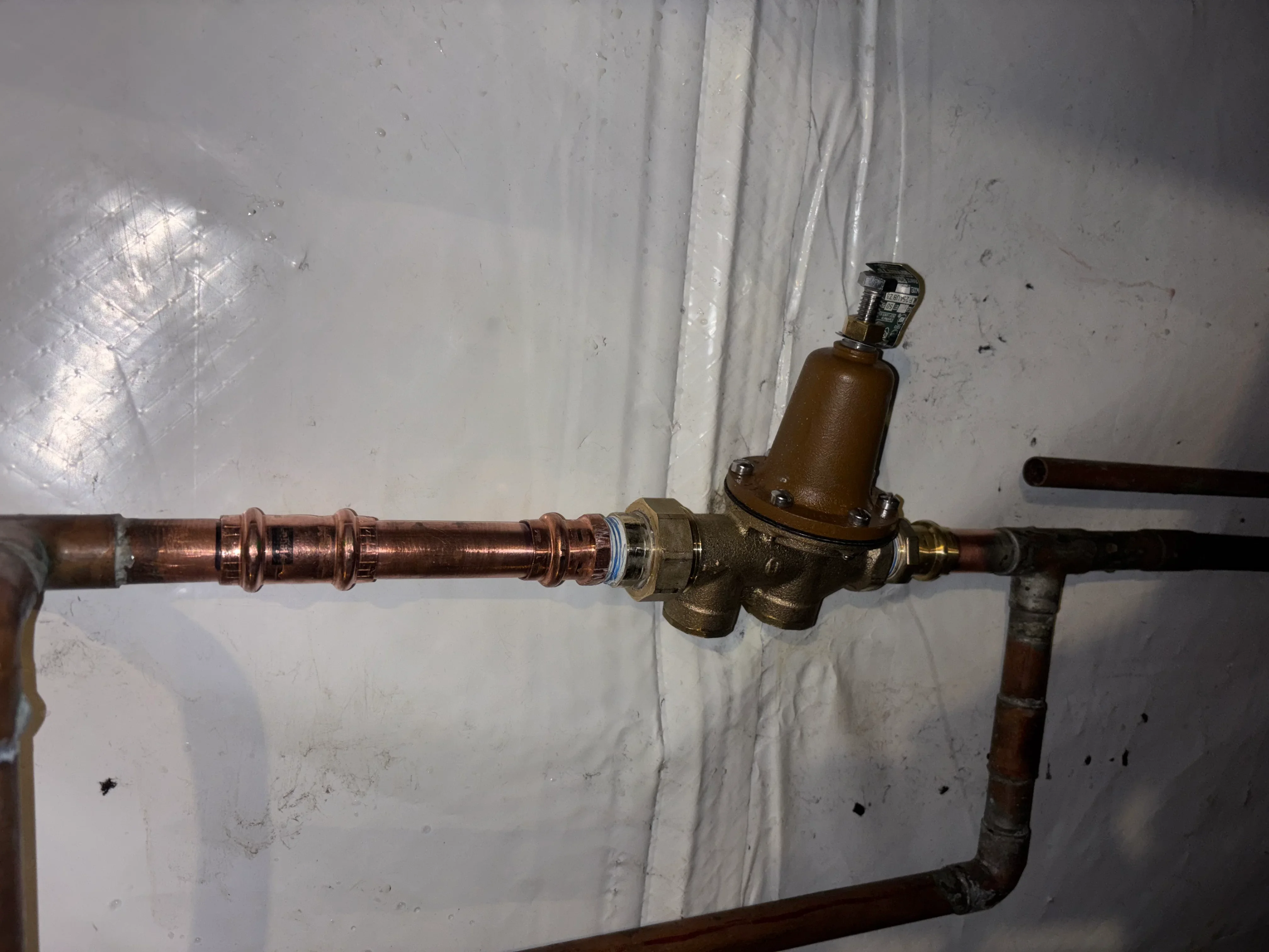 Brass pressure reducing valve installed on copper water line with compression fittings