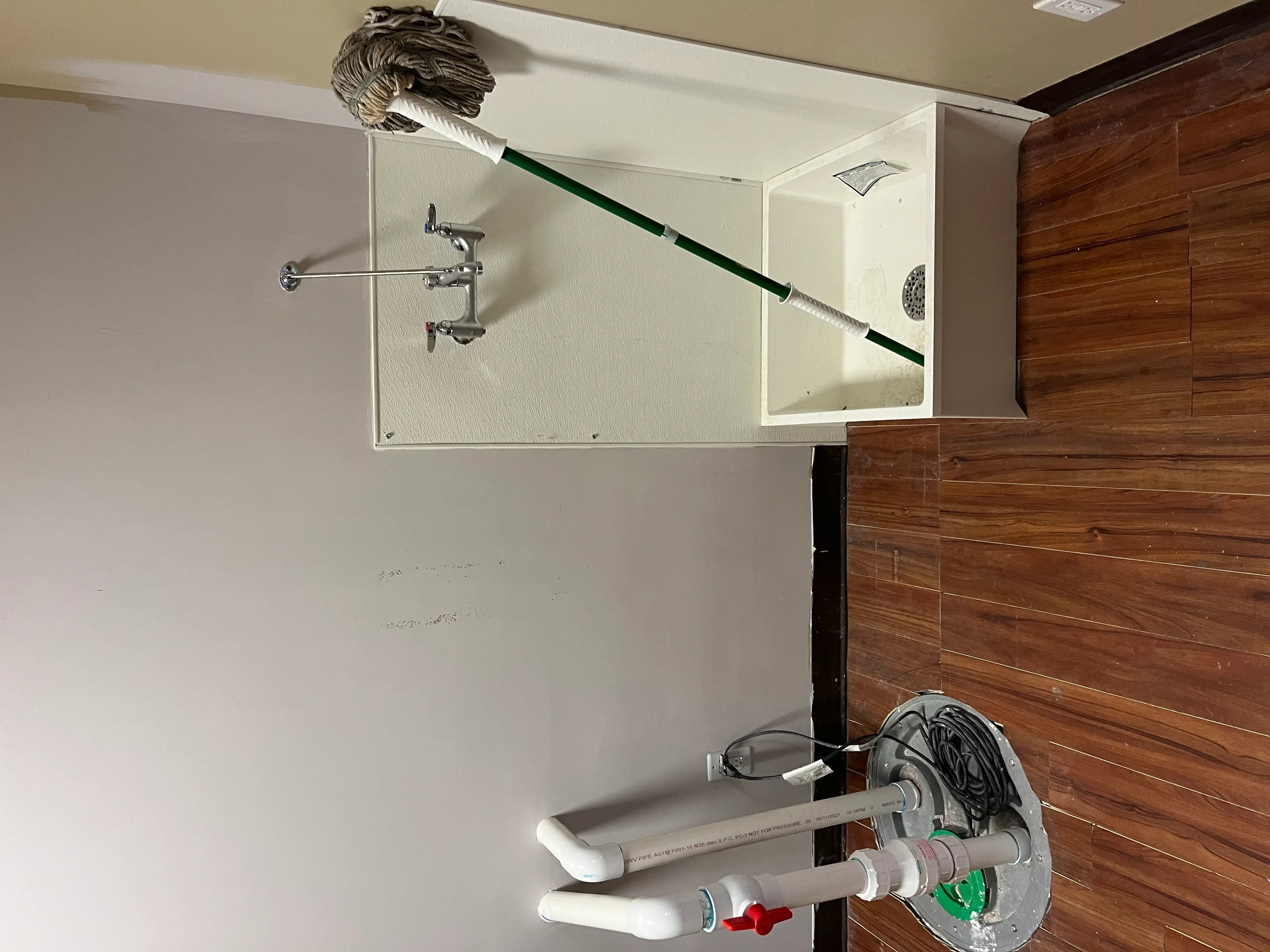 Chrome wall faucet, PVC drain pipes, and supply lines with shut-off valves in bathroom