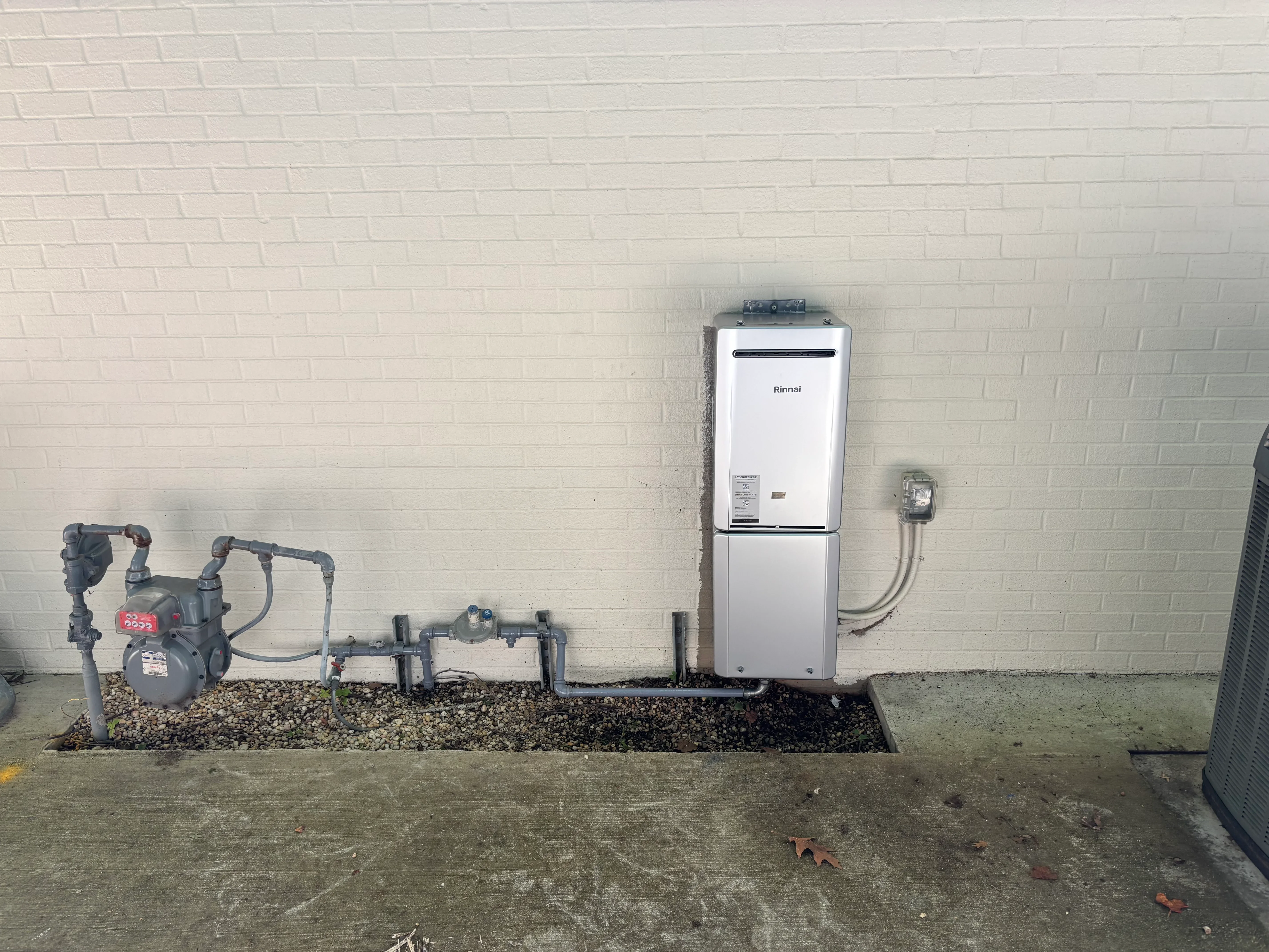Rinnai tankless water heater with PEX lines and isolation valves installed on brick wall