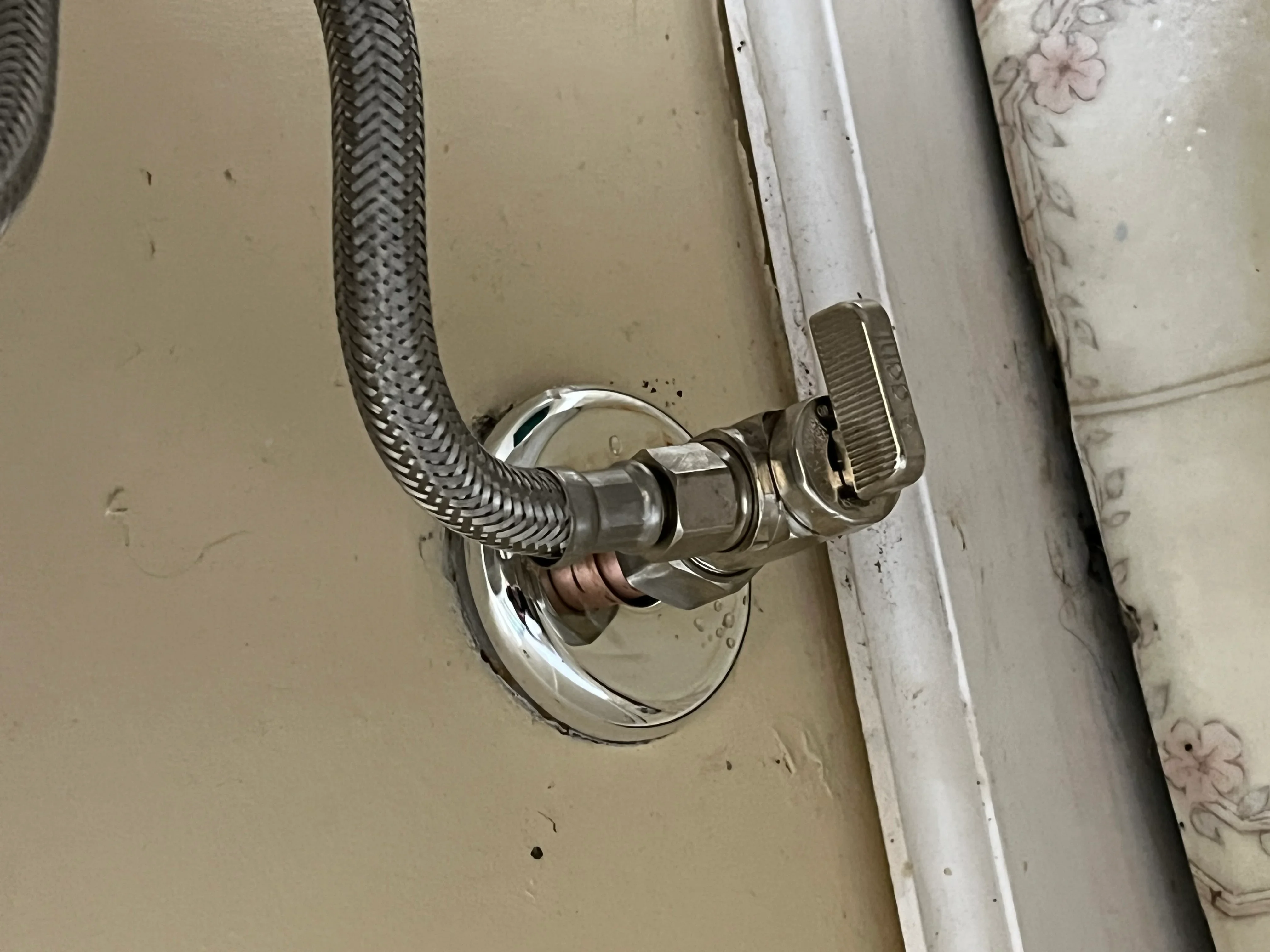 Chrome shut-off valve with braided stainless steel supply line connected to toilet