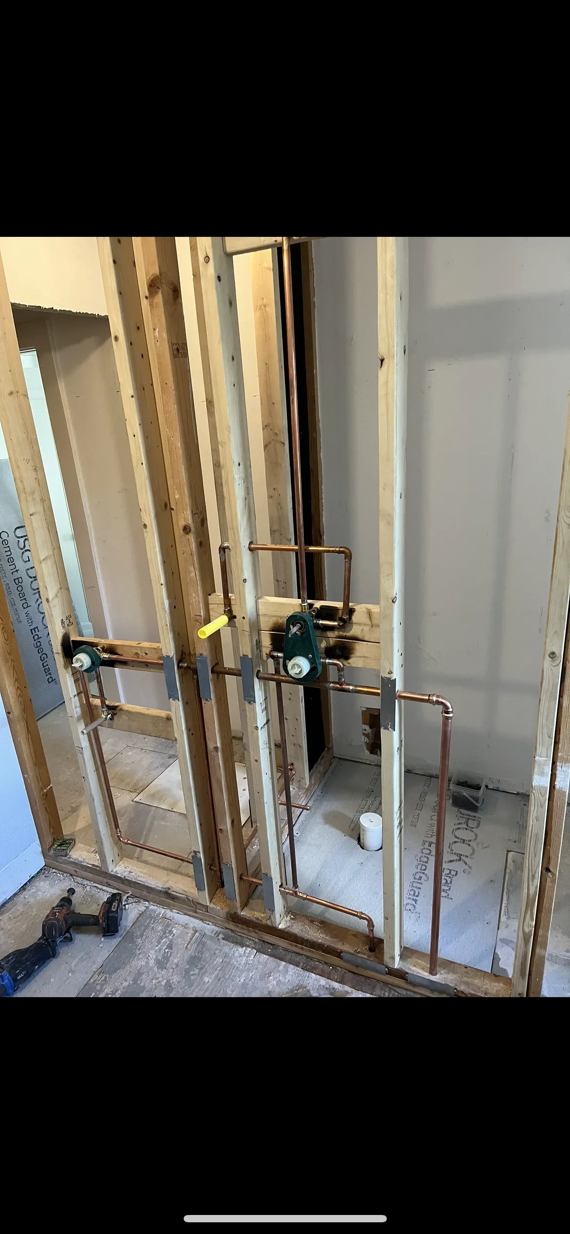 Copper and PVC plumbing lines installed in bathroom framing with supply and drain rough-in
