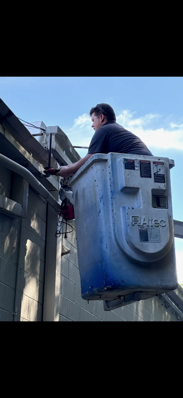 Technician on aerial lift performing gas line installation on concrete building exterior