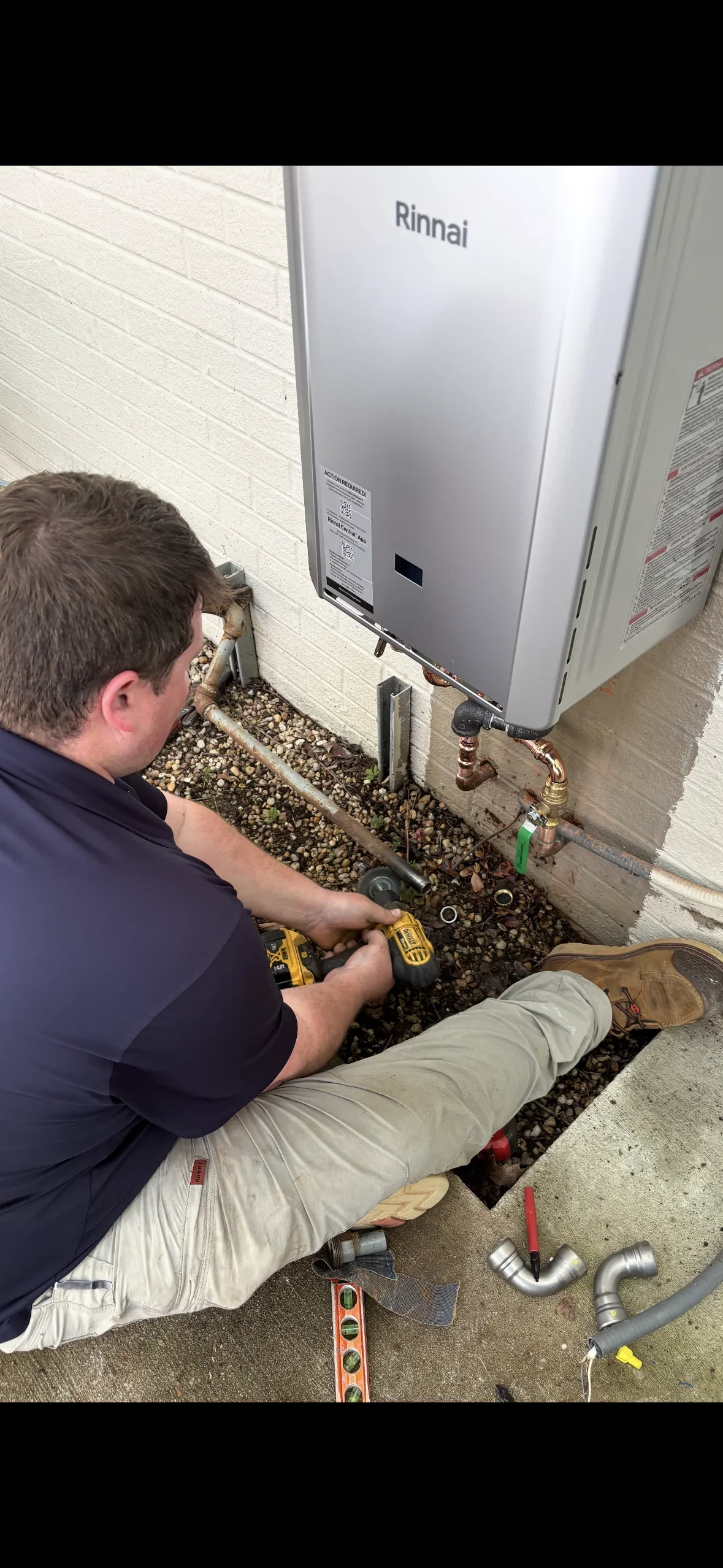 Technician installing Rinnai tankless water heater with copper piping connections