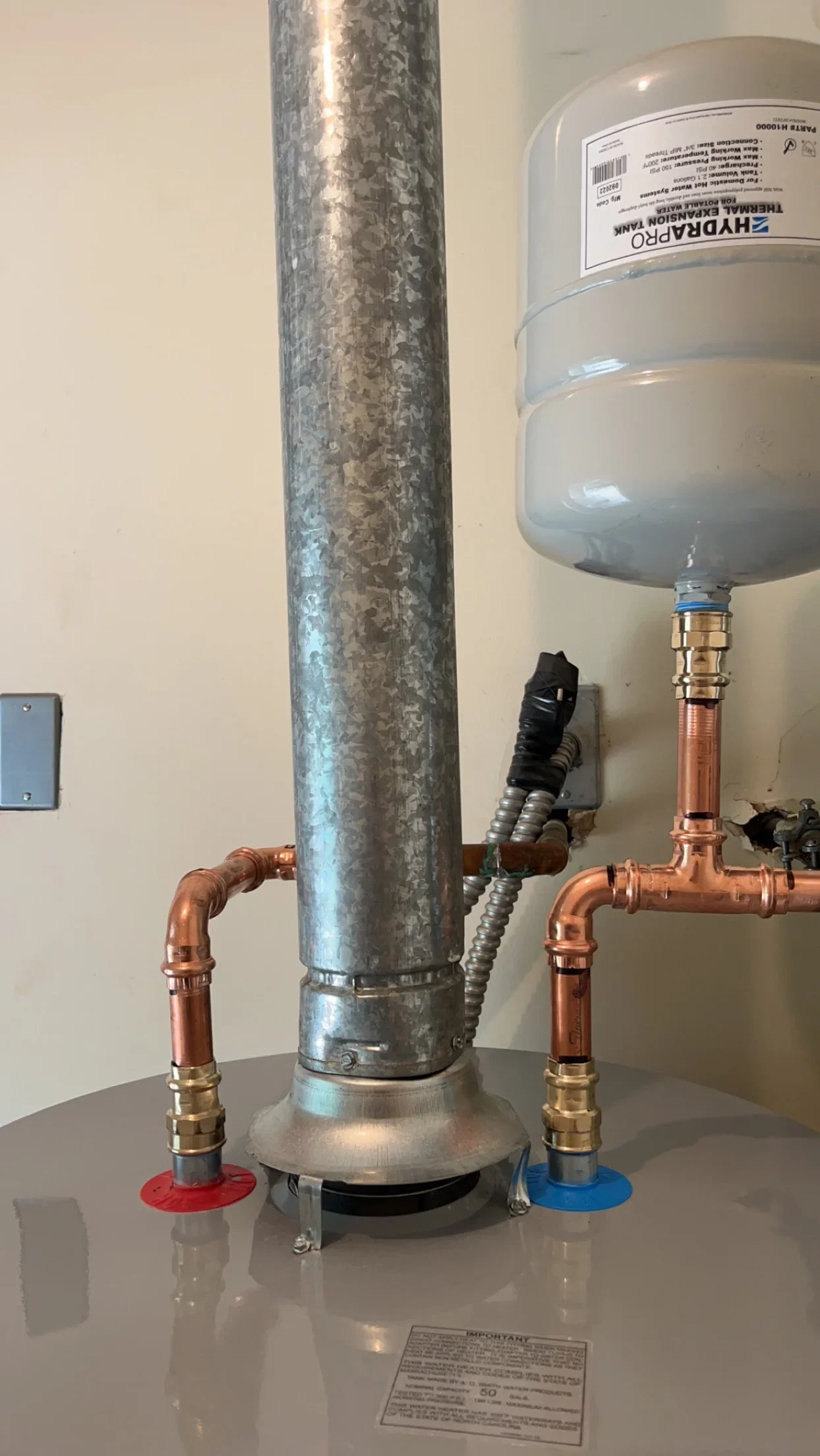 Water heater installation with copper piping, expansion tank, and color-coded shut-off valves