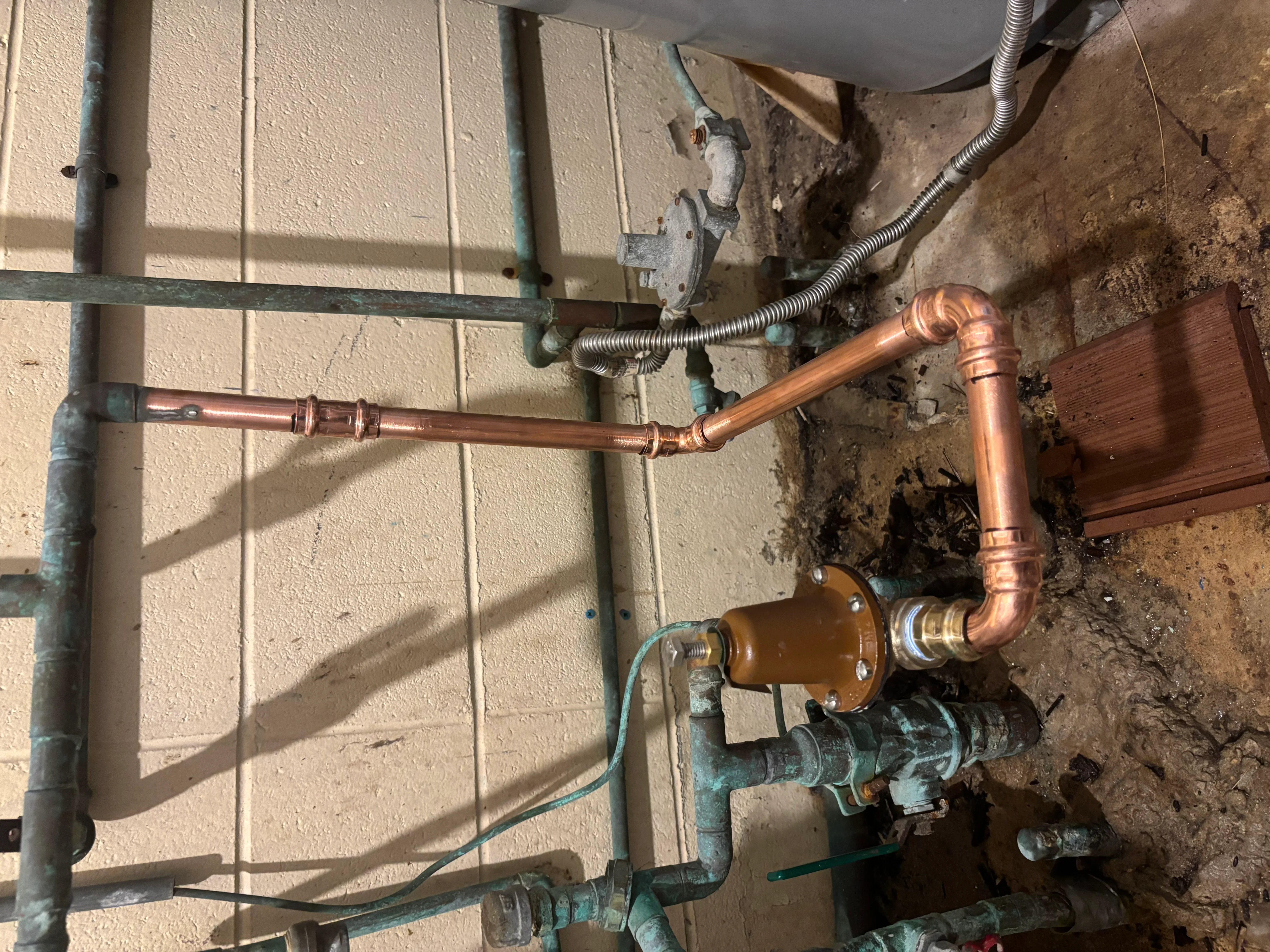 Soldered copper water lines with shut-off valve and flexible connectors on basement wall