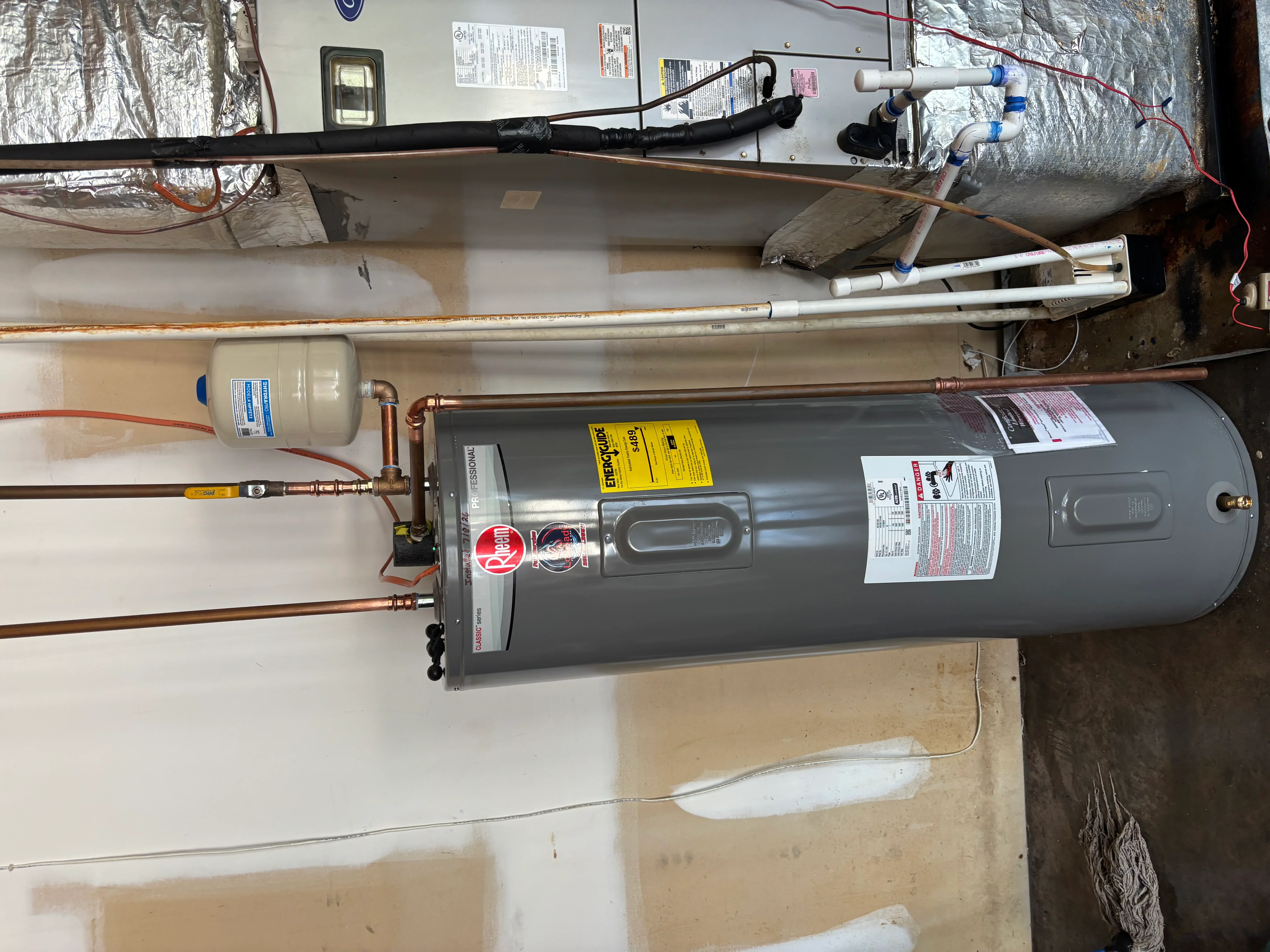 Electric water heater with copper piping, pressure relief valve, and insulated supply lines installed