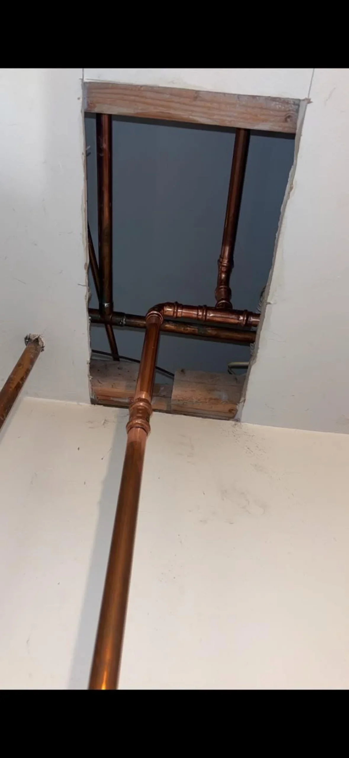 Copper pipe installation with soldered joints and fittings routed through ceiling framing