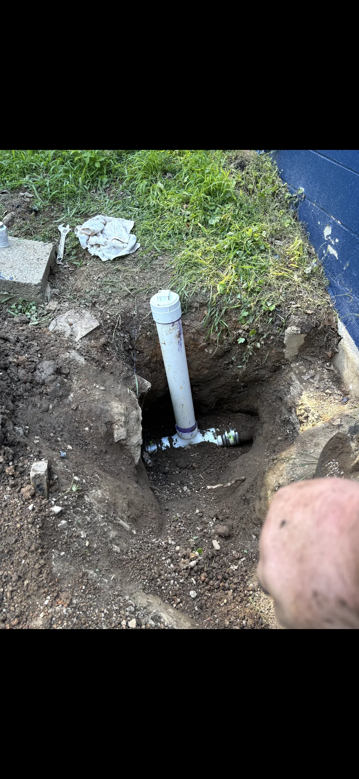 Underground water line installation with white PVC pipe and brass valve in excavated trench
