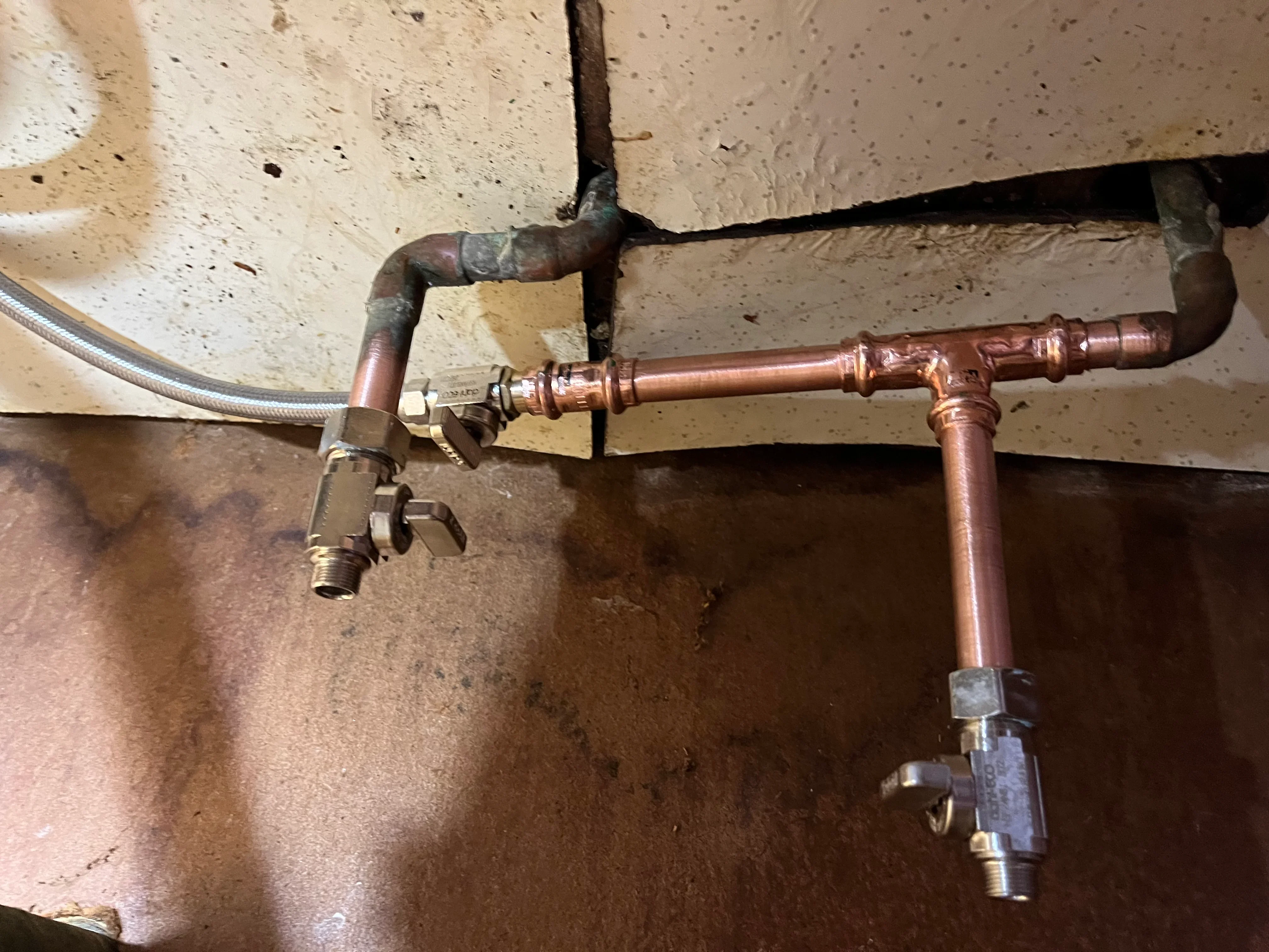 Copper pipe installation with soldered joints, ball valves, and shutoff valve on concrete ceiling
