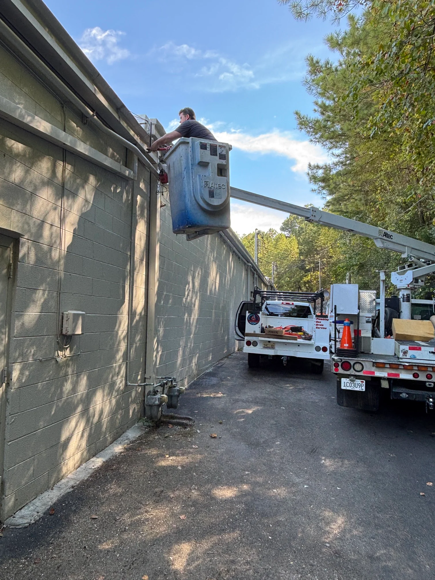 Technician on aerial lift installing gas line along residential soffit and gutter