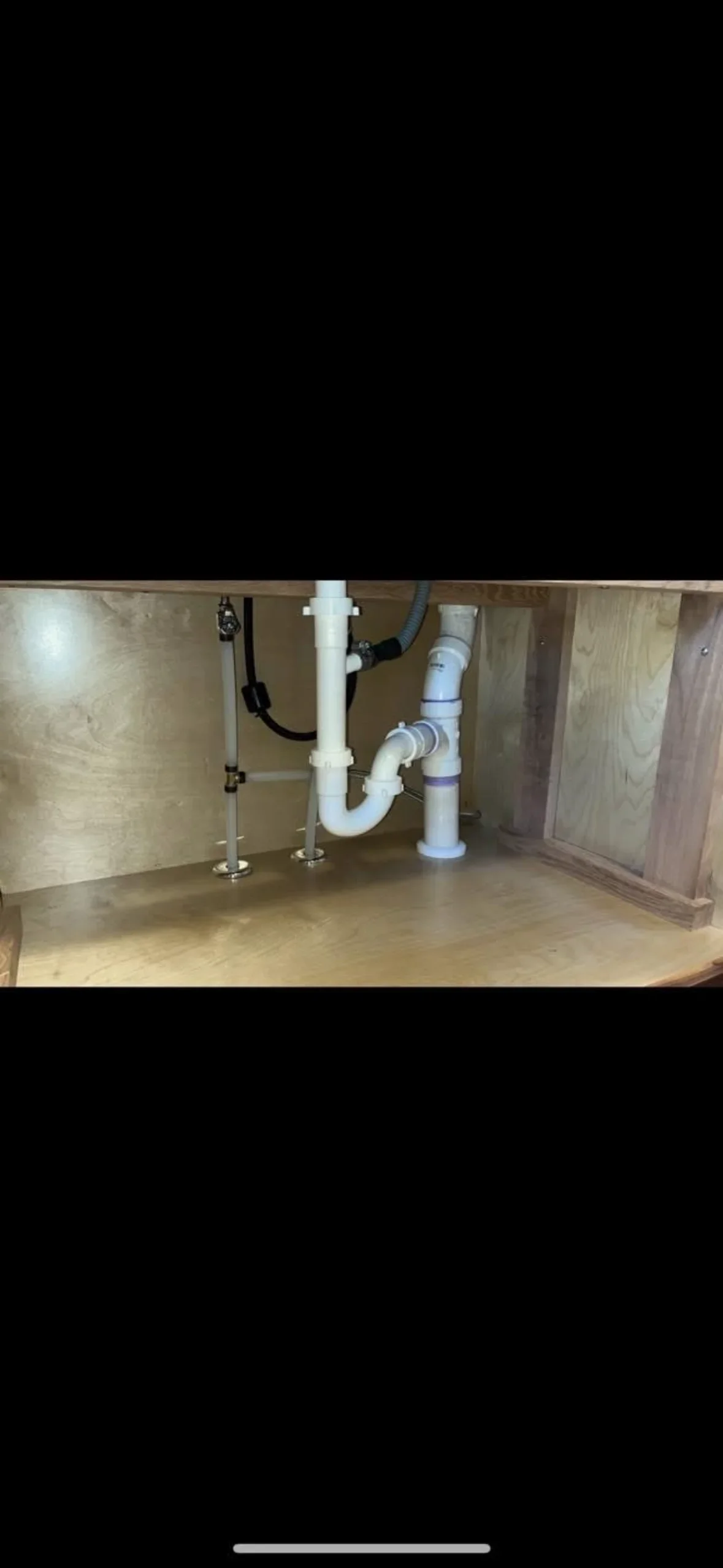 Under-sink plumbing with PVC pipes, P-trap, and shut-off valves installed in cabinet